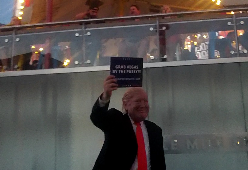 A Donald Trump Busker has a sign that many think is funny and many think is inappropriate.